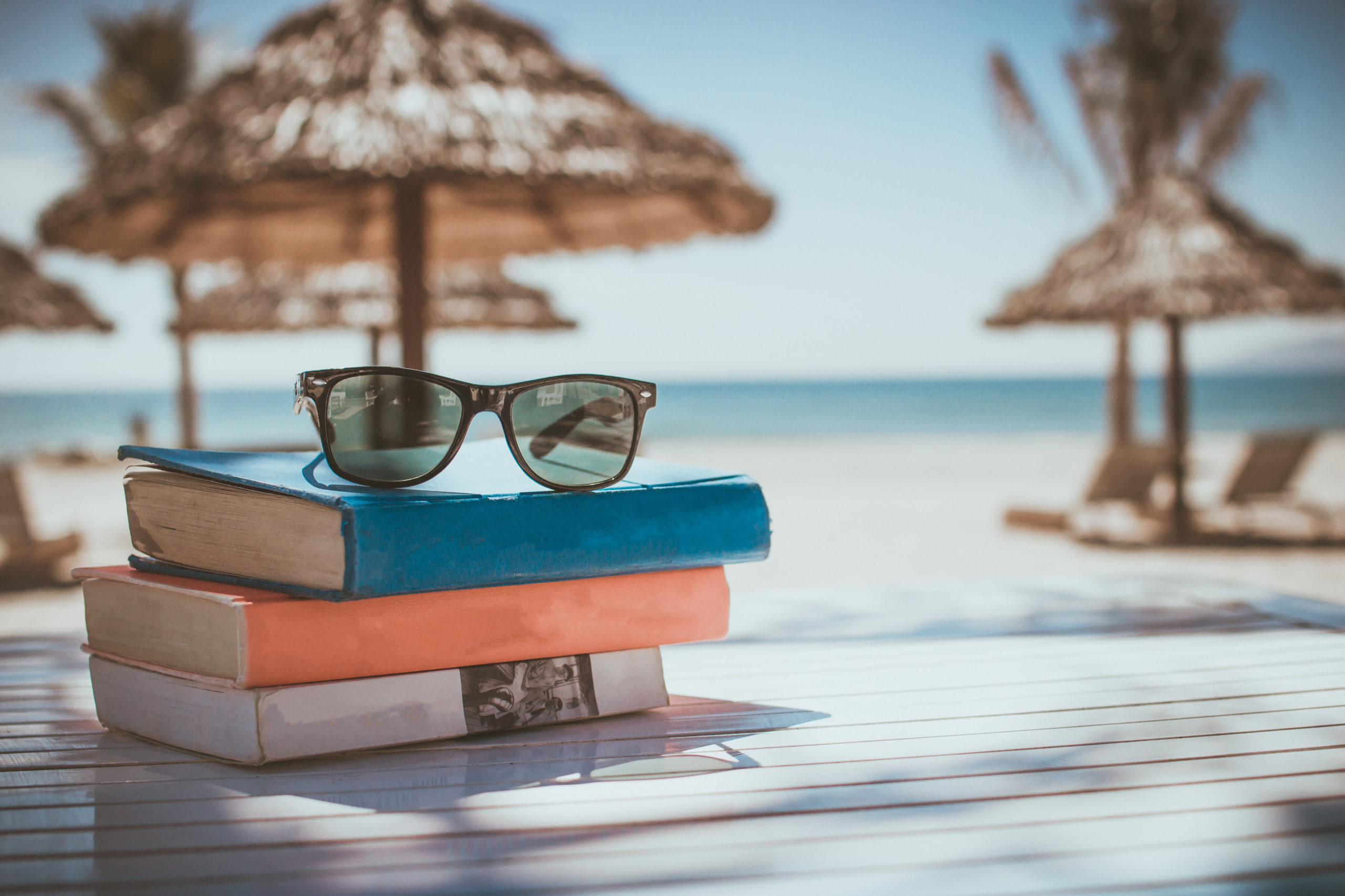 Summer Beach Scene with Books and Sunglasses and a Tiki Hut in the Background